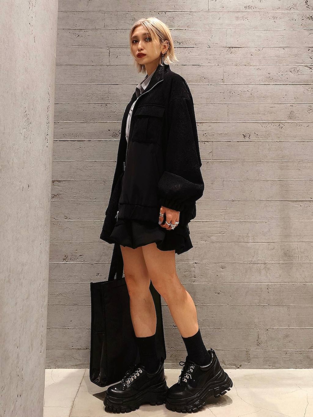 ブラック系のトートバッグ、ブラック系のスニーカー、ブラック系のスカートを着用したレディースの冬コーディネートの3枚目の写真