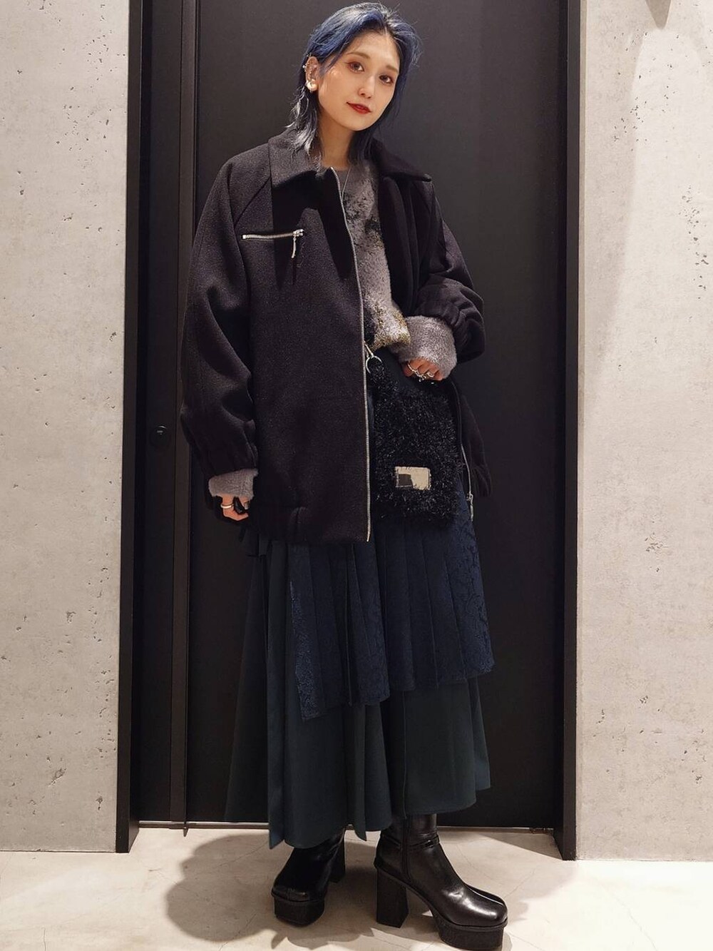 ブラック系のブルゾン、グリーン系のスカート、ブラック系のブーツを着用したレディースの秋コーディネートの2枚目の写真