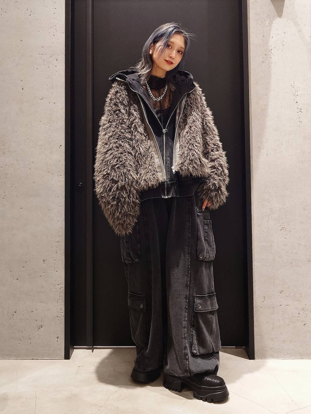 ブラック系のパーカー、ブラック系のカーゴパンツ、ブラック系のブーツを着用したレディースの秋コーディネートの3枚目の写真