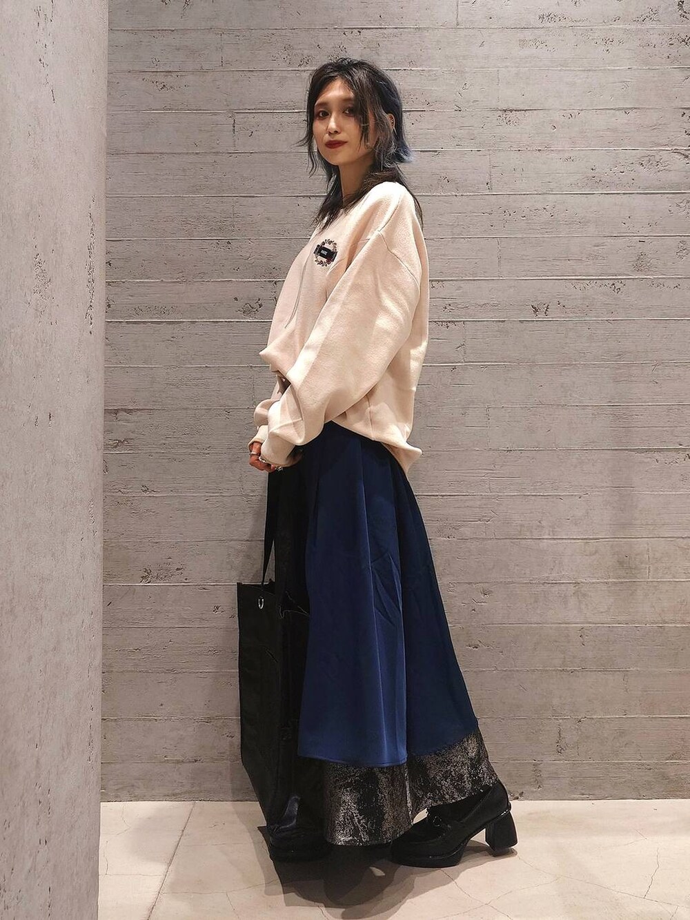 ブラック系のトートバッグ、ブルー系のスカート、ブラック系のローファーを着用したレディースの秋コーディネートの2枚目の写真