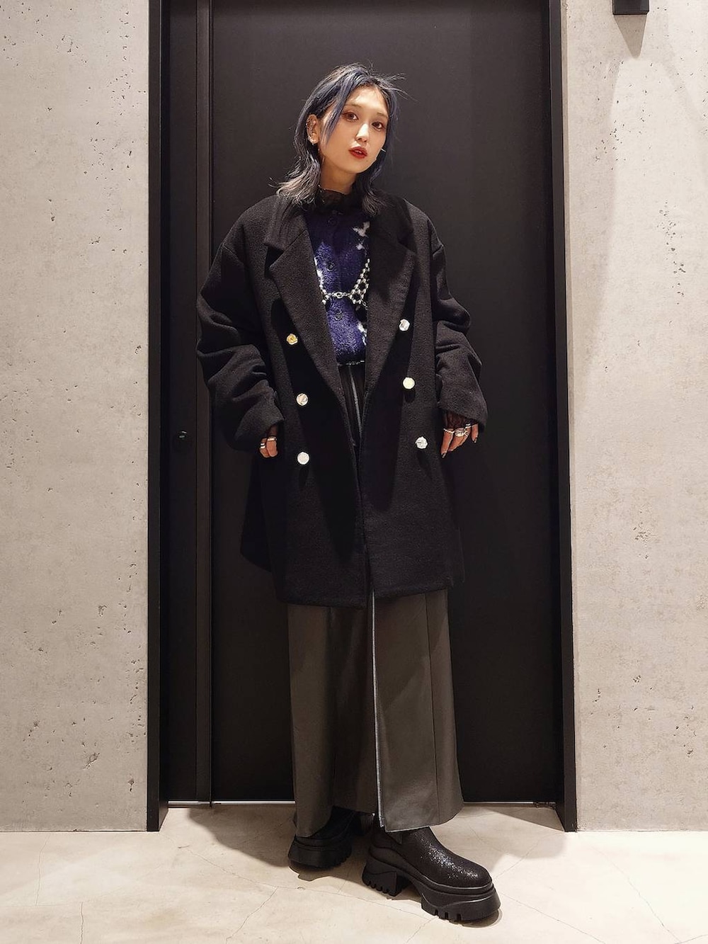 ブラック系のチェスターコート、パープル系のカーディガン/ボレロ、ブラック系のブーツを着用したレディースの冬コーディネートの2枚目の写真
