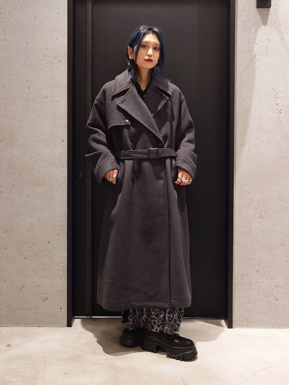 グレー系のトレンチコート、ブラック系のブーツ、ブラック系のショルダーバッグを着用したレディースの冬コーディネートの3枚目の写真