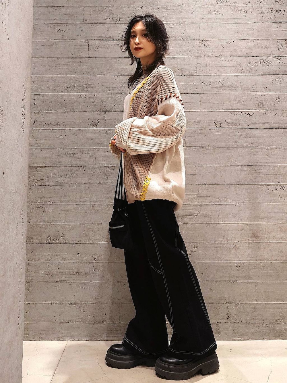 ブラック系のショルダーバッグ、ブラック系のデニムパンツ、ホワイト系のニット/セーターを着用したレディースの秋コーディネートの2枚目の写真