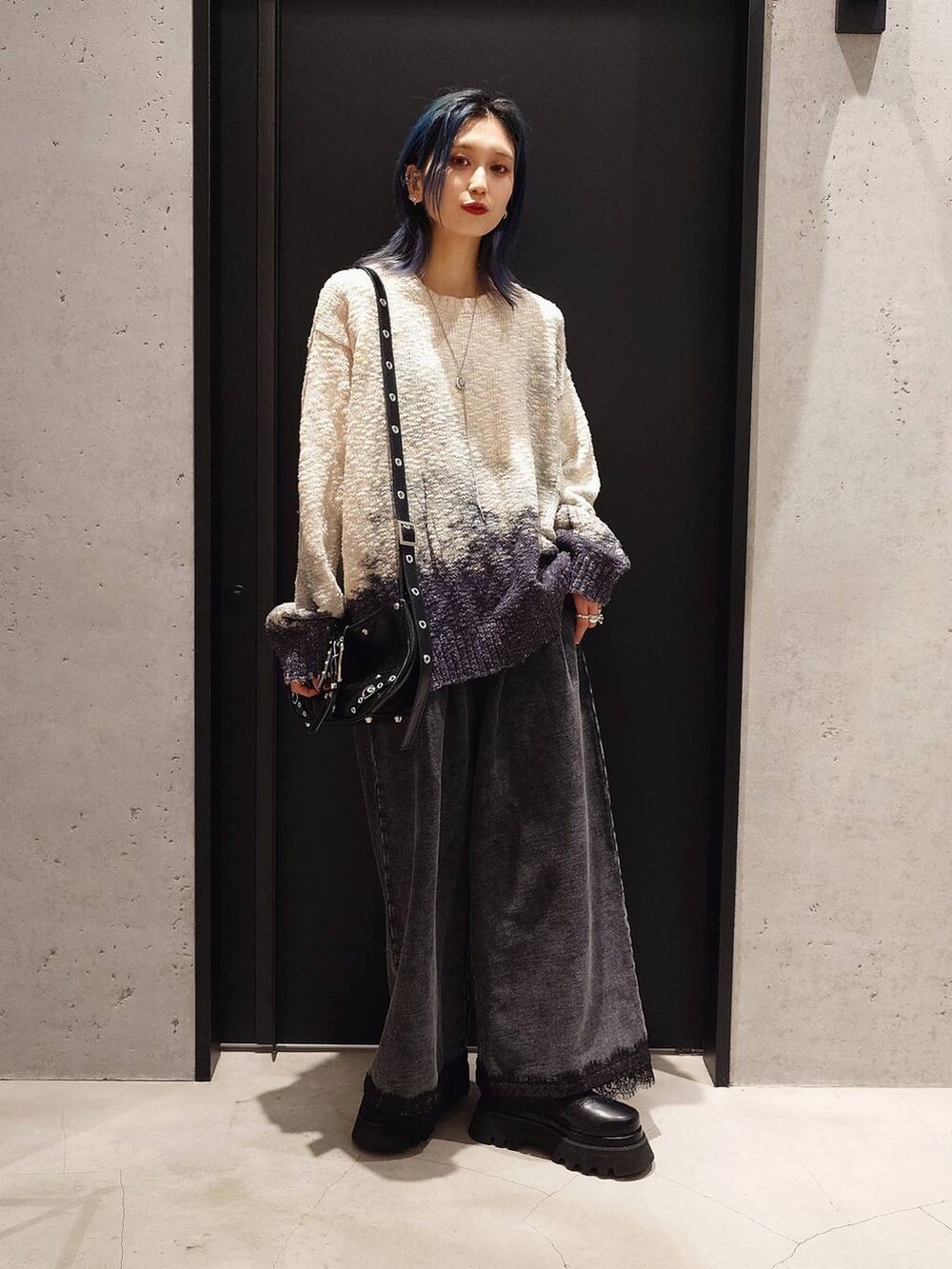 ブラック系のショルダーバッグ、ブラック系のスウェットパンツ、ブラック系のブーツを着用したレディースの冬コーディネートの2枚目の写真