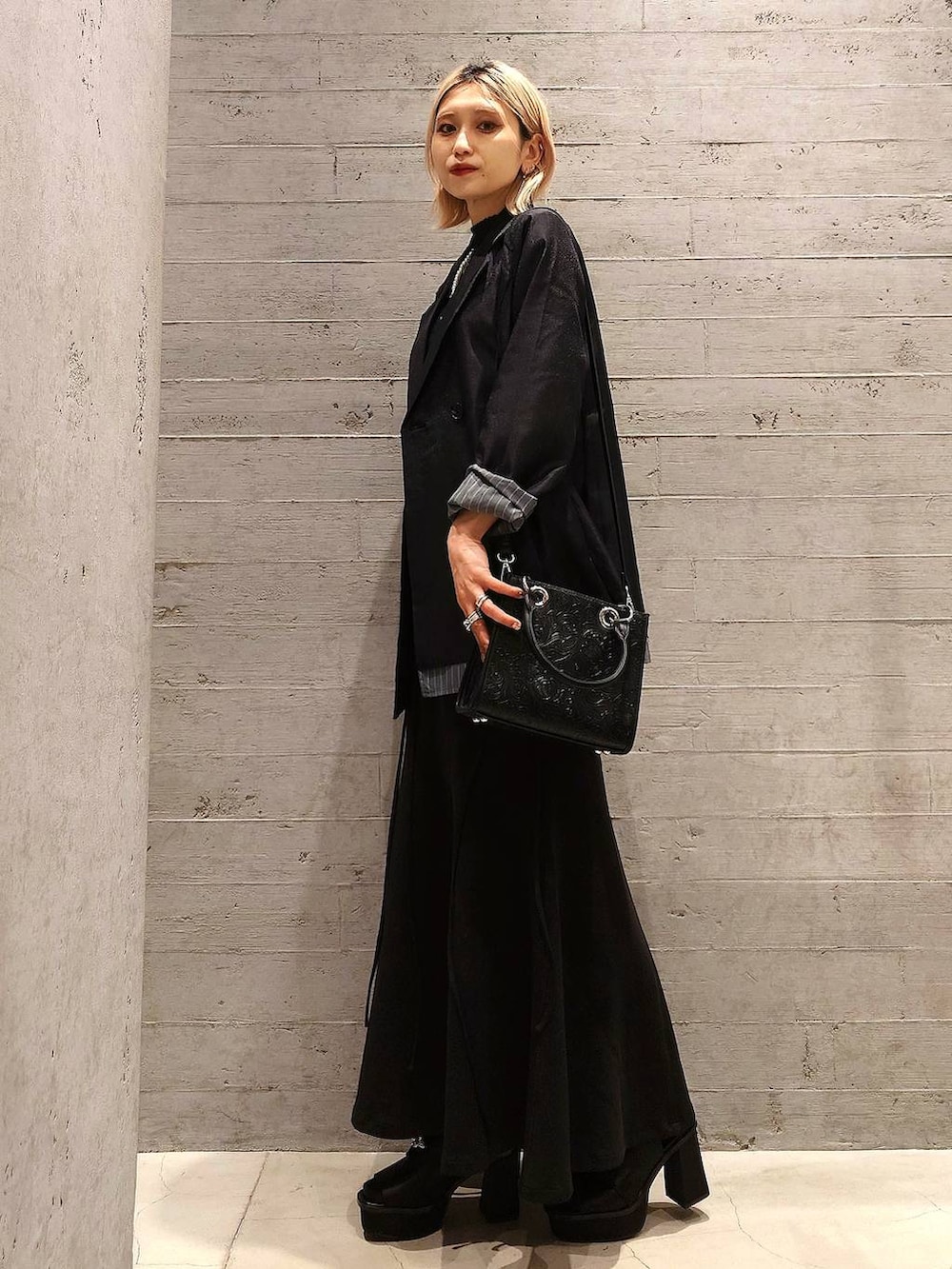 ブラック系のショルダーバッグ、ブラック系のテーラードジャケット、ブルー系のニット/セーターを着用したレディースの春コーディネートの3枚目の写真