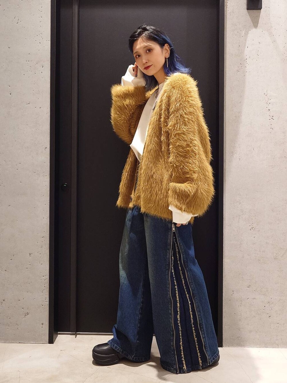 ブルー系のデニムパンツ、ブラック系のブーツ、イエロー系のカーディガン/ボレロを着用したレディースの秋コーディネートの2枚目の写真