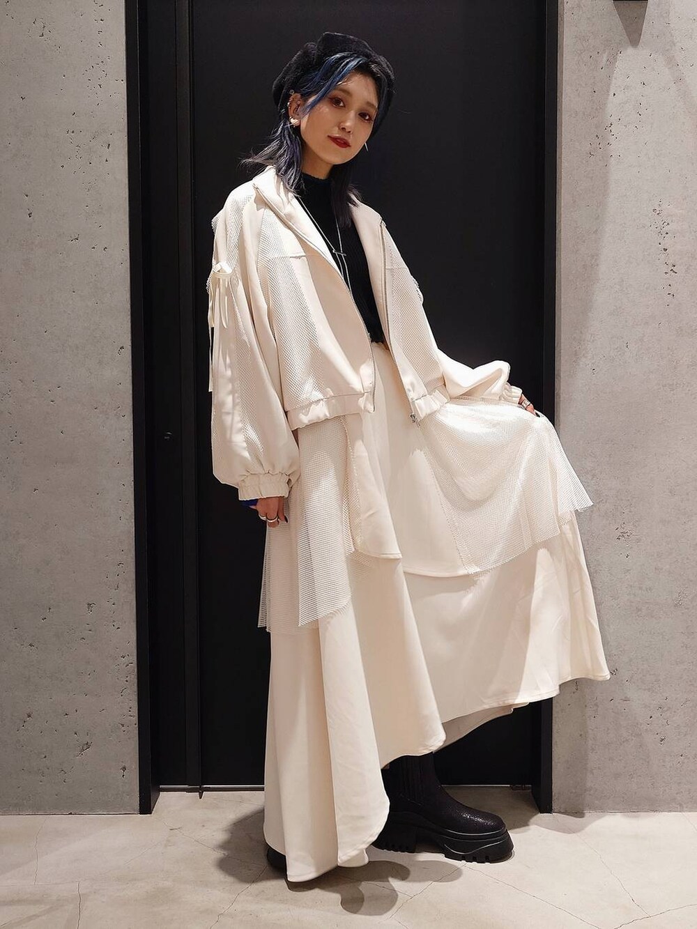 ブラック系のニット/セーター、ブラック系のブーツ、ホワイト系のスカートを着用したレディースの冬コーディネートの3枚目の写真