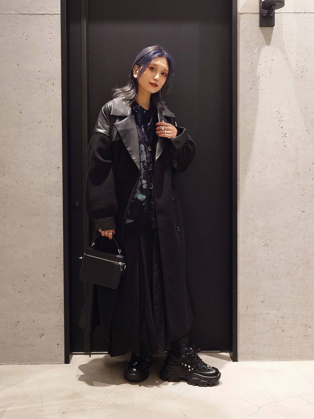 ブラック系のチェスターコート、ブラック系のカーディガン/ボレロ、ブラック系のスニーカーを着用したレディースの秋コーディネートの2枚目の写真