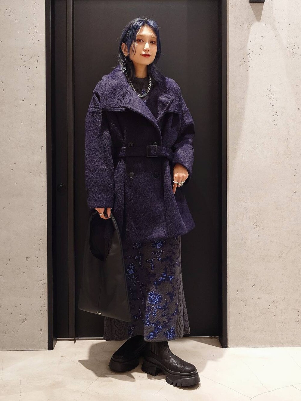 グレー系のニット/セーター、ブラック系のトートバッグ、グレー系のスカートを着用したレディースの秋コーディネートの3枚目の写真