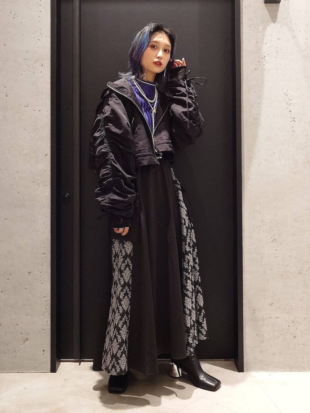 パープル系のニット/セーター、ブラック系のブーツ、ブラック系のスカートを着用したレディースの秋コーディネートの2枚目の写真