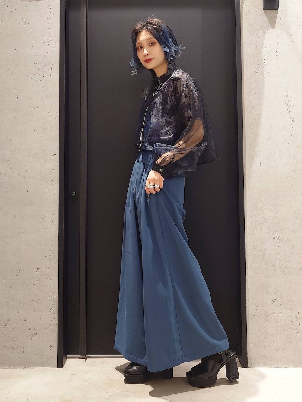 ブラック系のショルダーバッグ、ブラック系のサンダル、ブルー系のスラックスを着用したレディースの春コーディネートの2枚目の写真