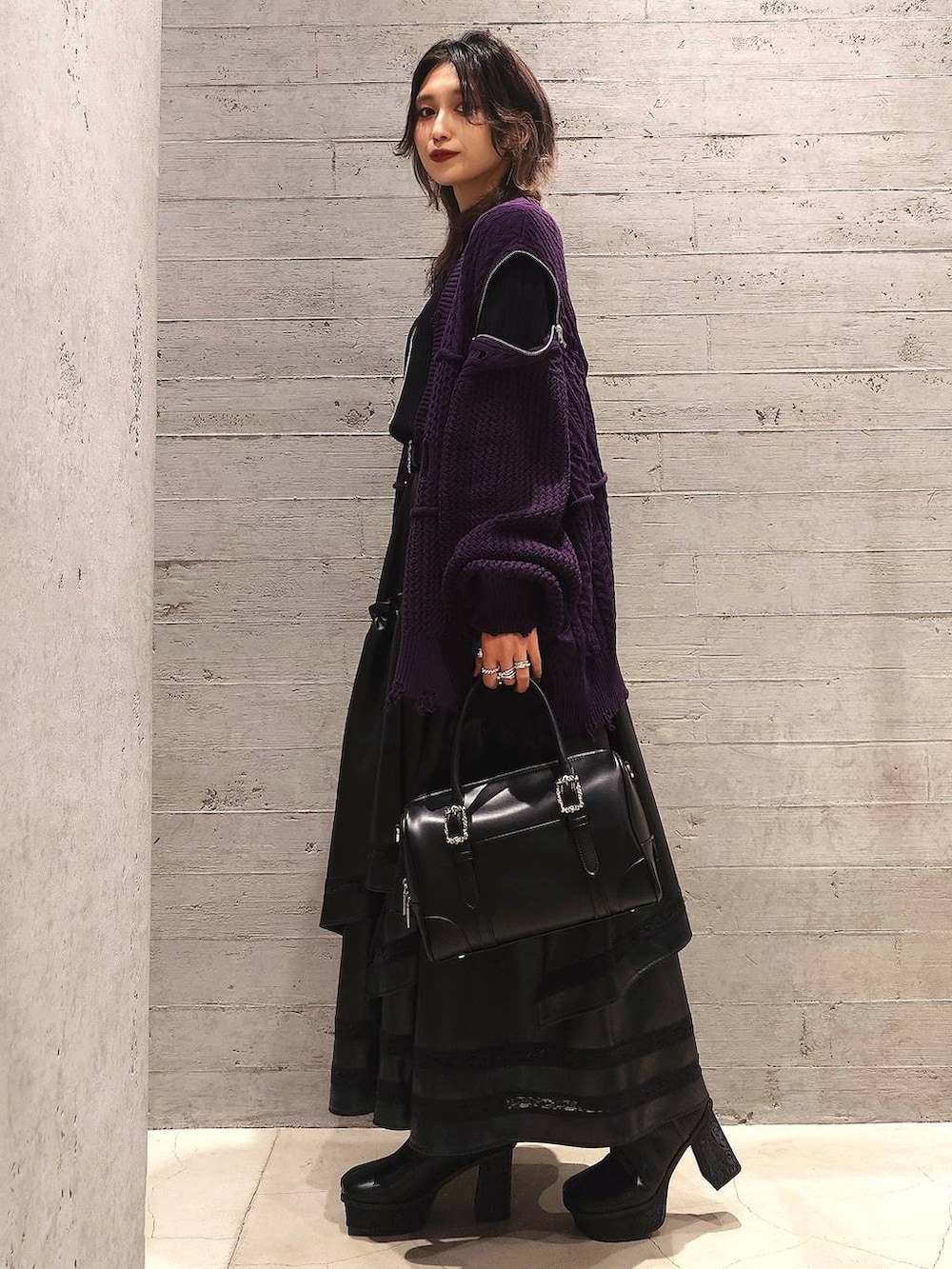 ブラック系のニット/セーター、ブラック系のボストンバッグ、ブラック系のブーツを着用したレディースの秋コーディネートの2枚目の写真