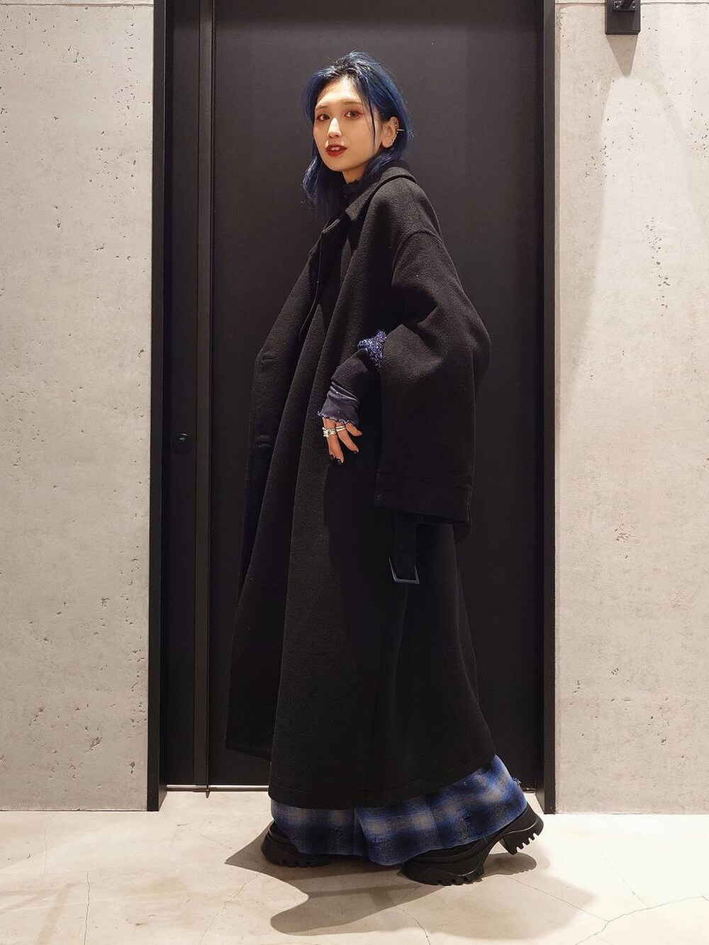 ブラック系のトレンチコート、ブラック系のブーツ、ブルー系のTシャツ/カットソーを着用したレディースの冬コーディネートの3枚目の写真