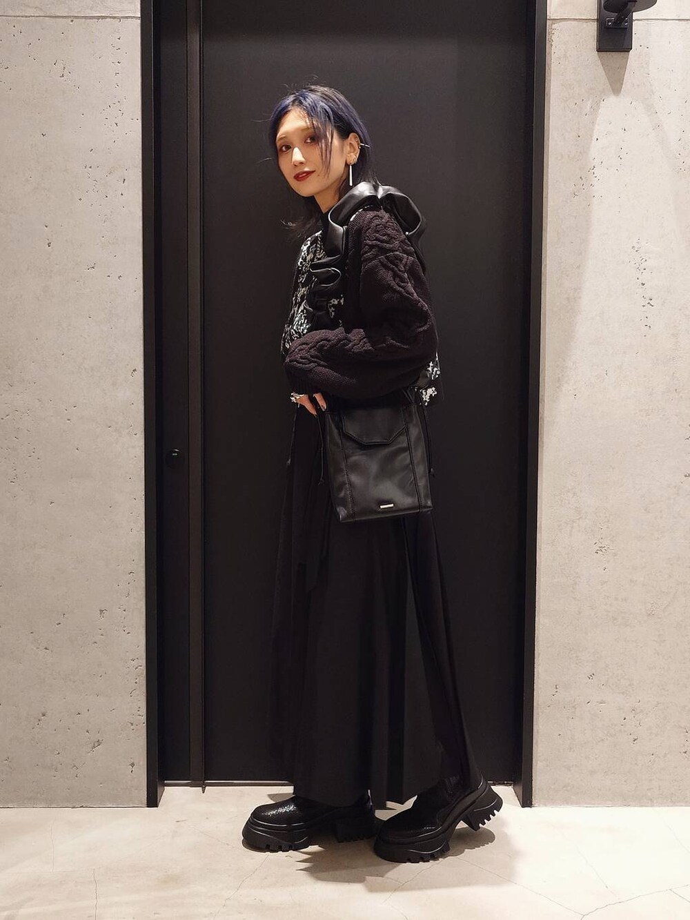 ブラック系のチェスターコート、ブラック系のニット/セーター、ブラック系のブーツを着用したレディースの秋コーディネートの2枚目の写真