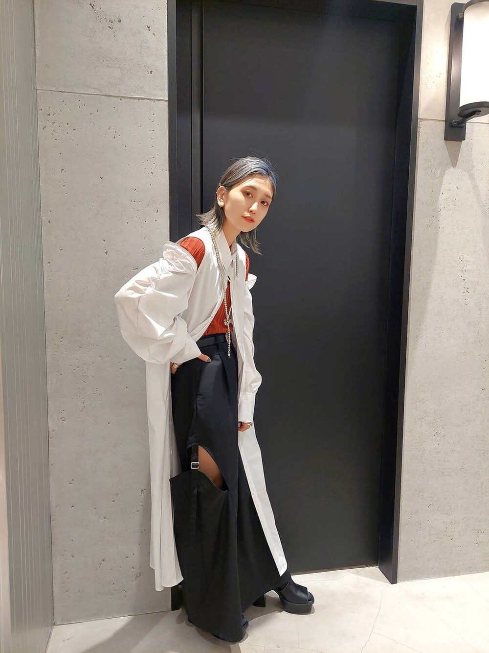 ブラック系のサンダル、ホワイト系のワンピース、オレンジ系のニット/セーターを着用したレディースの春コーディネートの3枚目の写真