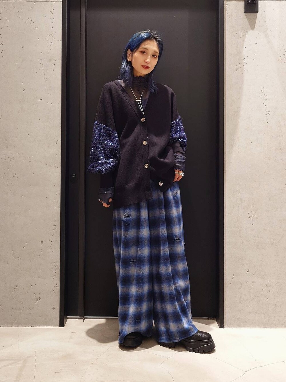 ブラック系のトレンチコート、ブラック系のブーツ、ブルー系のTシャツ/カットソーを着用したレディースの冬コーディネートの2枚目の写真