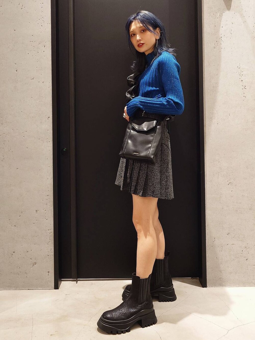 ブルー系のチェスターコート、ブルー系のニット/セーター、ブラック系のブーツを着用したレディースの秋コーディネートの2枚目の写真