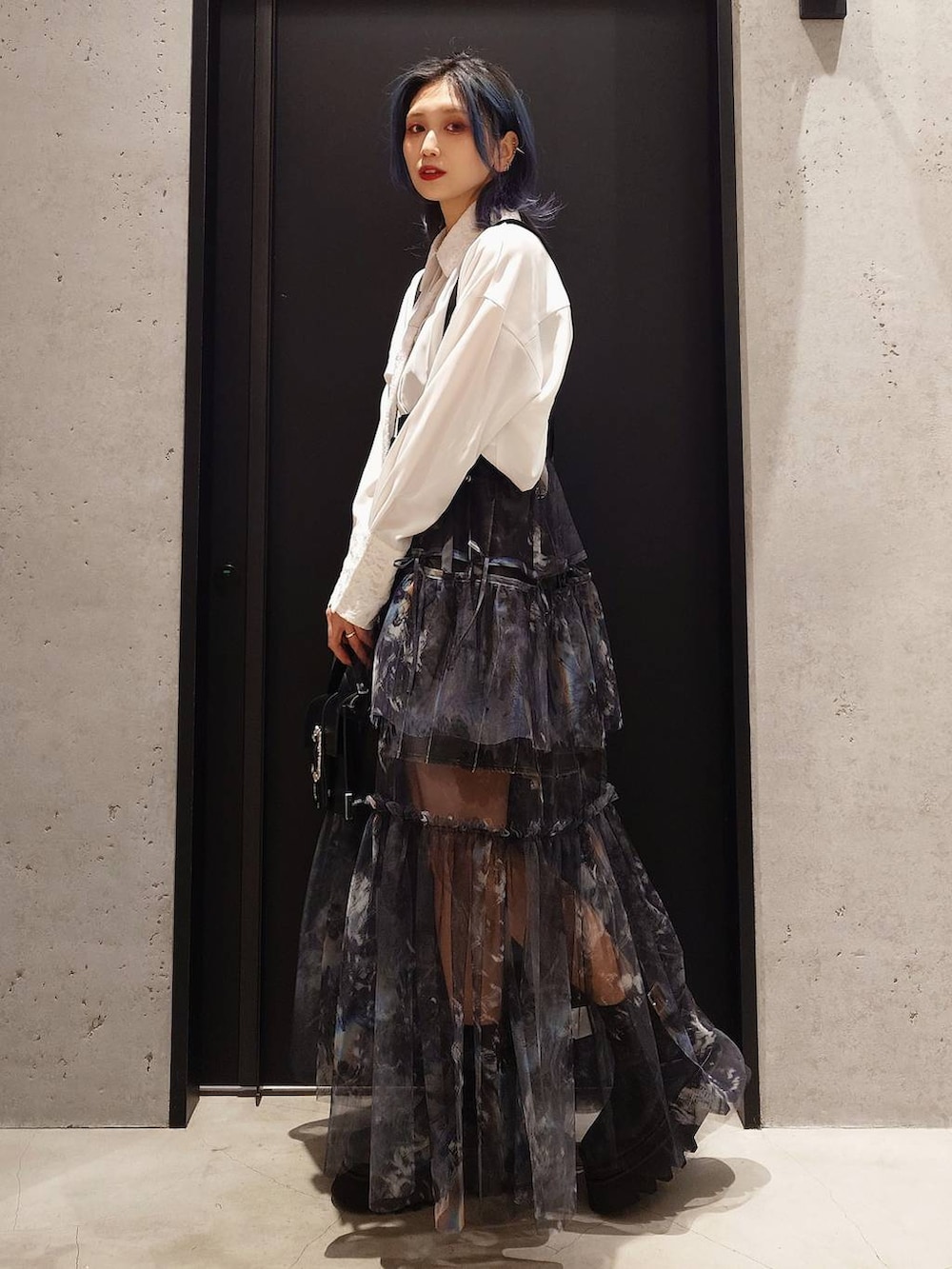 グレー系のスカート、ブラック系のショルダーバッグ、ブラック系のブーツを着用したレディースの冬コーディネートの2枚目の写真