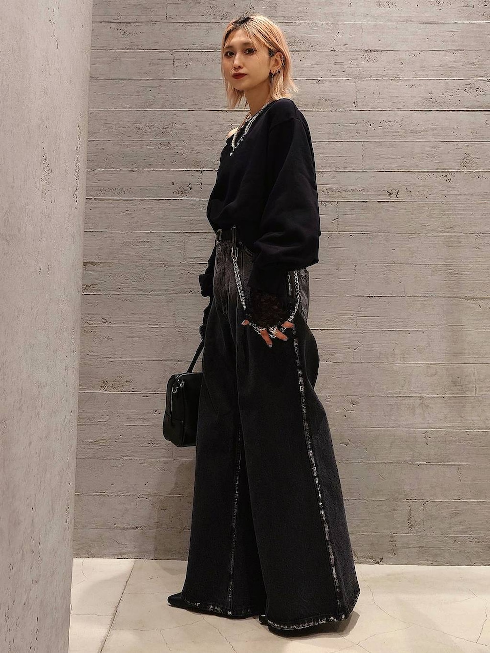 ブラック系のボストンバッグ、ブラック系のパンプス、ブラック系のデニムパンツを着用したレディースの冬コーディネートの2枚目の写真