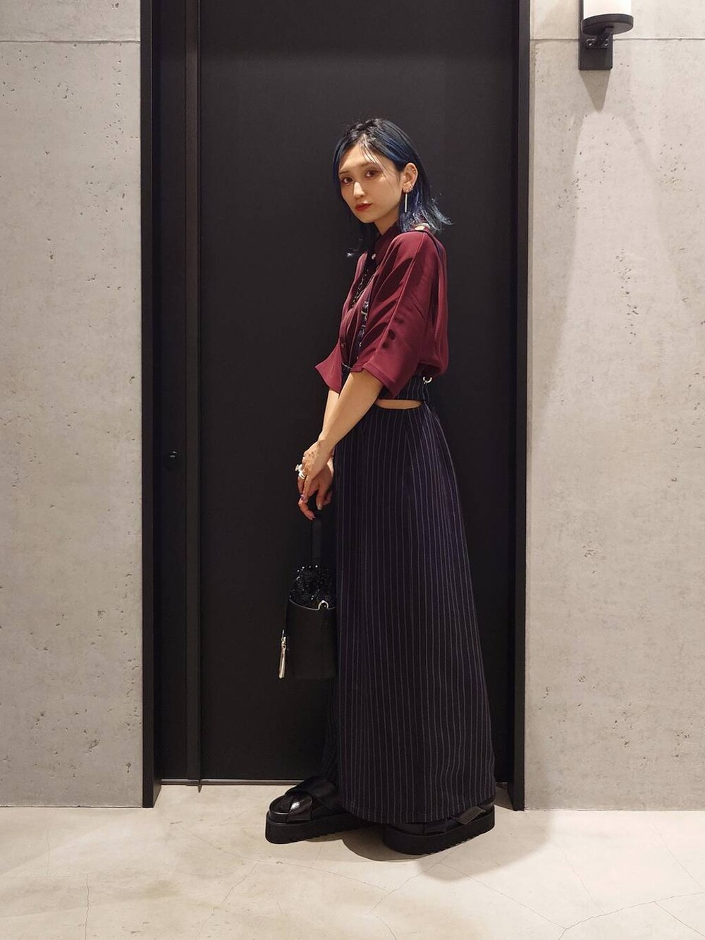 ブラック系のサンダル、レッド系のシャツ/ブラウス、ブラック系のショルダーバッグを着用したレディースの春コーディネートの2枚目の写真