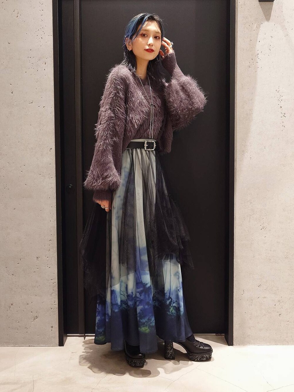 グレー系のニット/セーター、グリーン系のスカート、ブラック系のブルゾンを着用したレディースの冬コーディネートの2枚目の写真