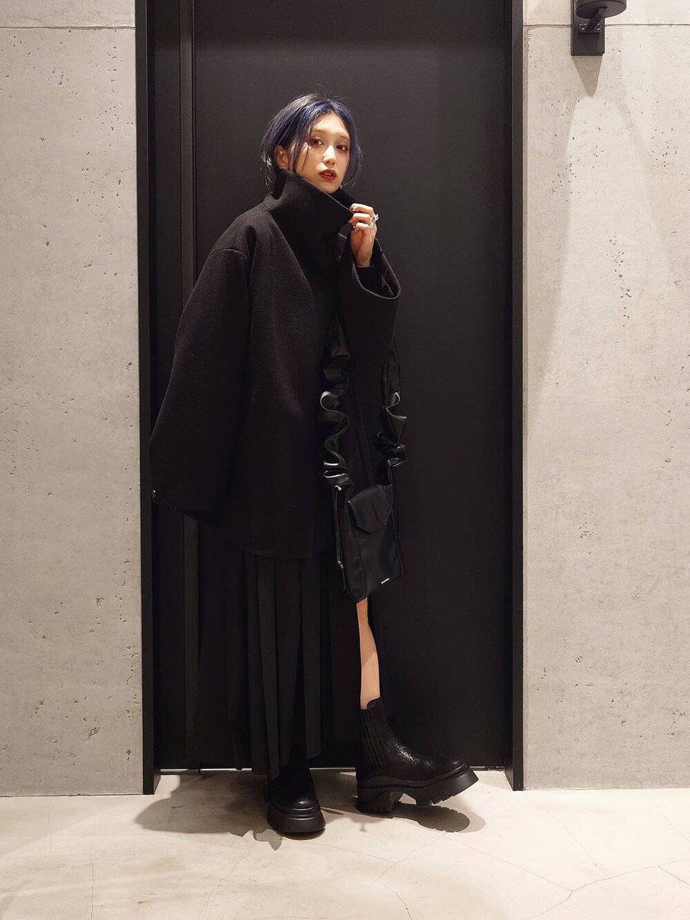 ブラック系のチェスターコート、ブラック系のニット/セーター、ブラック系のブーツを着用したレディースの秋コーディネートの3枚目の写真