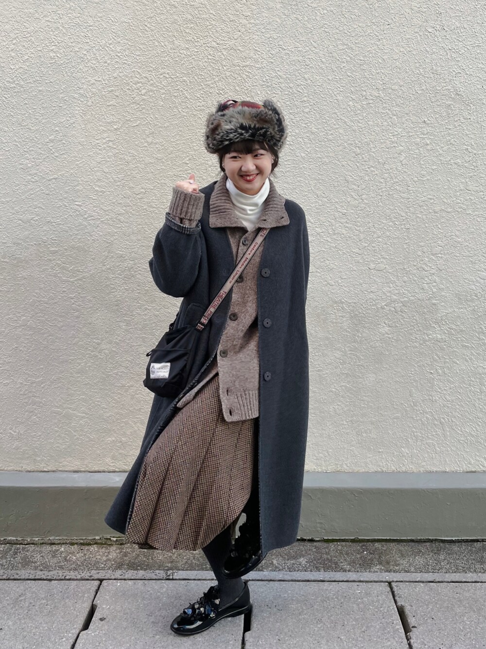 ブラック系のローファー、ブラック系のショルダーバッグ、ブラウン系のスカートを着用したレディースの冬コーディネートの2枚目の写真