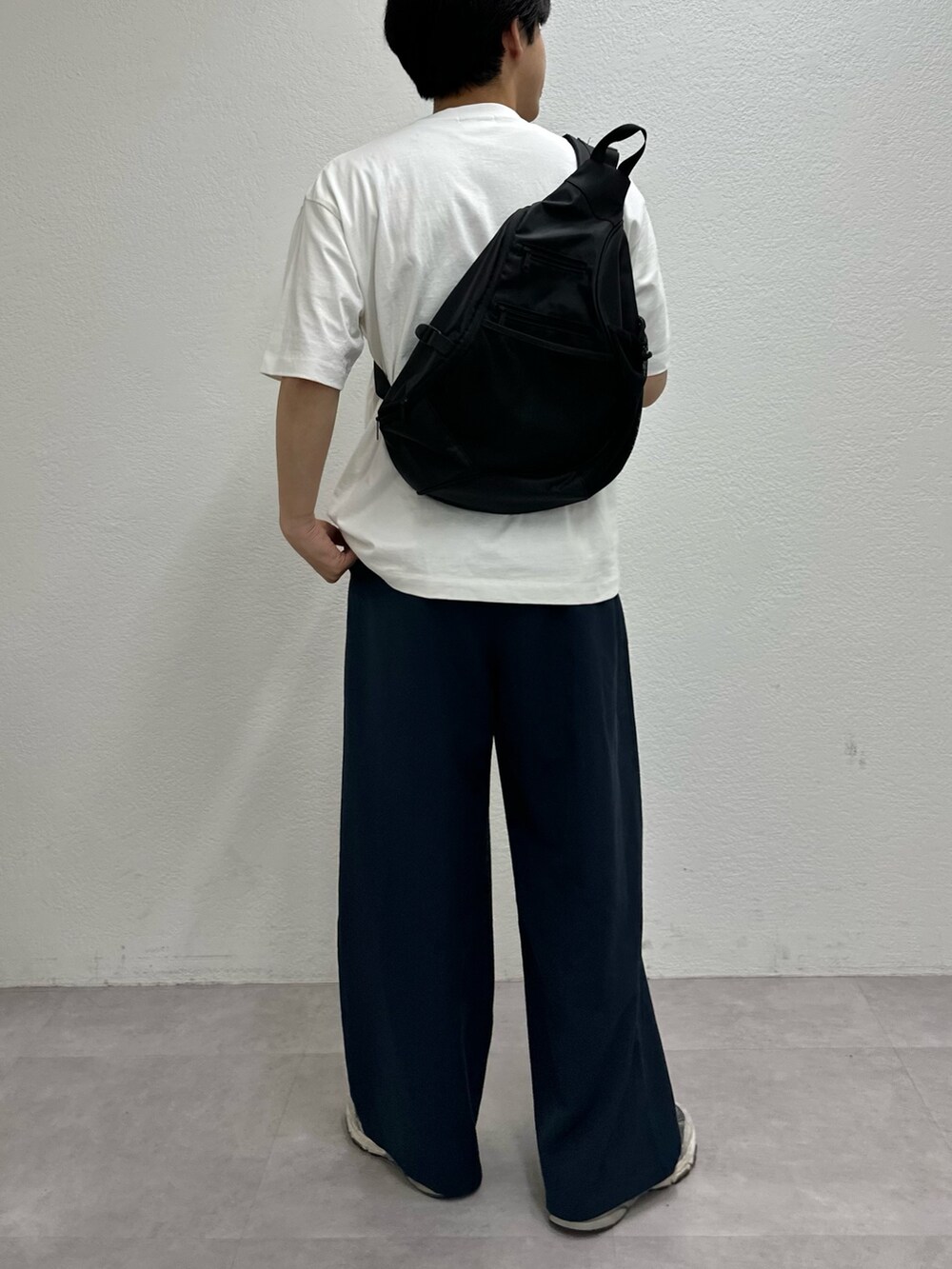 ホワイト系のTシャツ/カットソー、ブルー系のスラックス、ブラック系のショルダーバッグを着用したメンズの春コーディネートの2枚目の写真