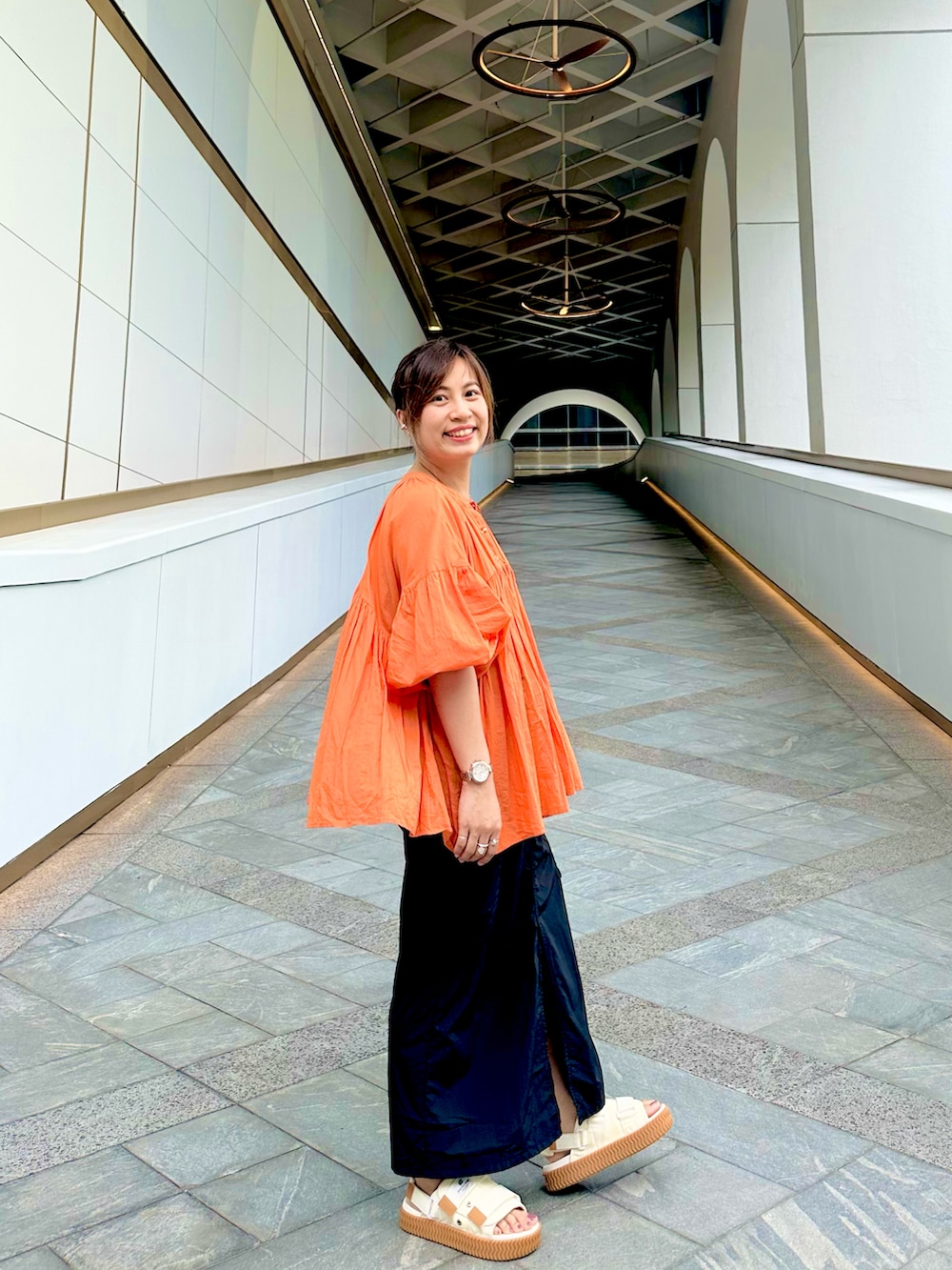 ブラック系のシャツ/ブラウス、ブラック系のスカート、ホワイト系のサンダルを着用したレディースの秋コーディネートの2枚目の写真