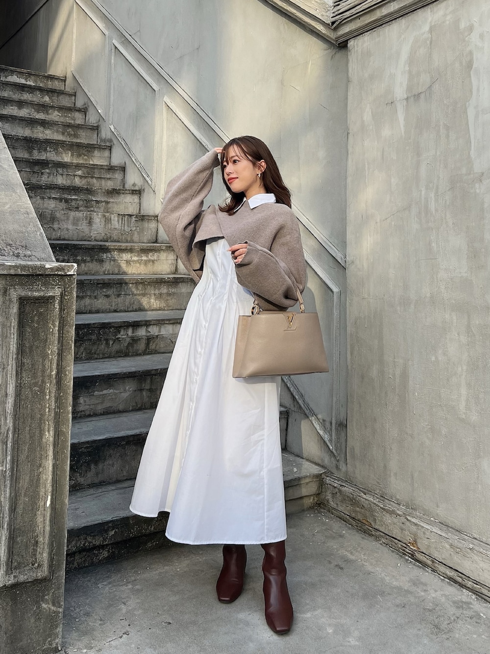 ブラウン系のブーツ、ベージュ系のバッグ、ホワイト系のシャツワンピースを着用したレディースの秋コーディネートの2枚目の写真