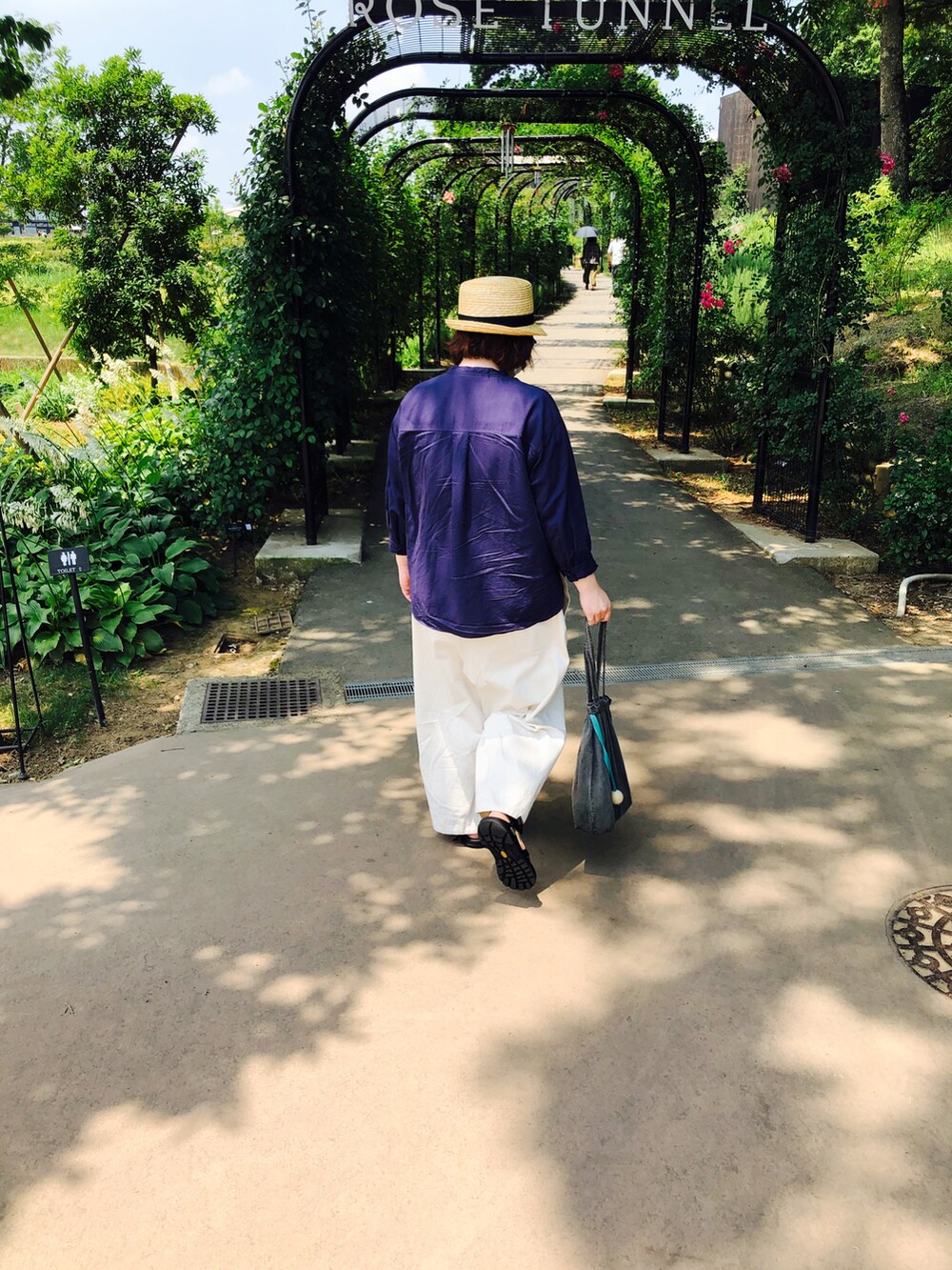 ブルー系のシャツ/ブラウス、ホワイト系のパンツ、グレー系のトートバッグを着用したレディースの夏コーディネートの2枚目の写真