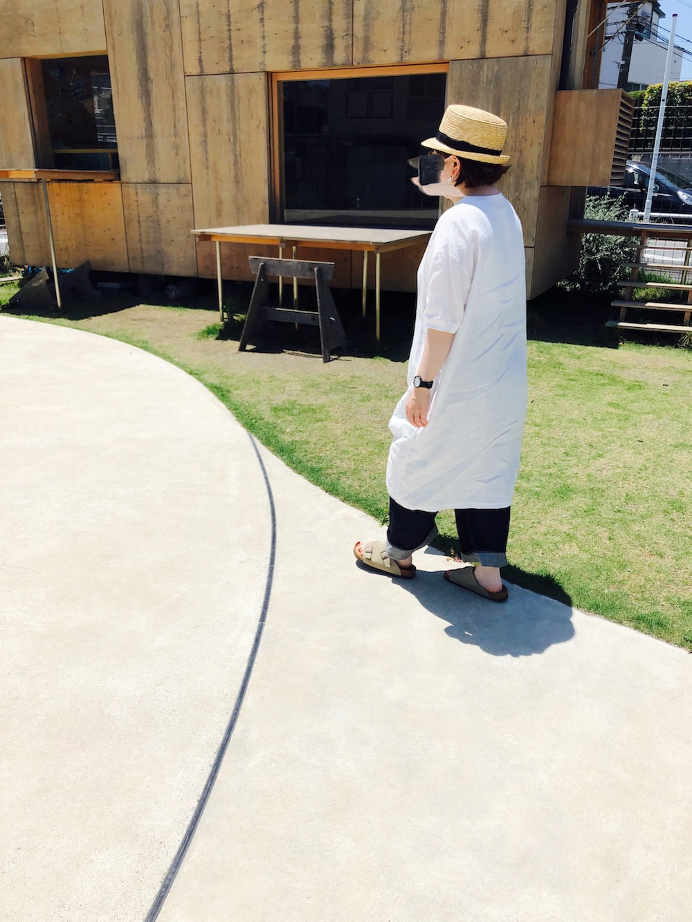 ホワイト系のワンピース、グリーン系のバッグ、ブルー系のデニムパンツを着用したレディースの夏コーディネートの2枚目の写真