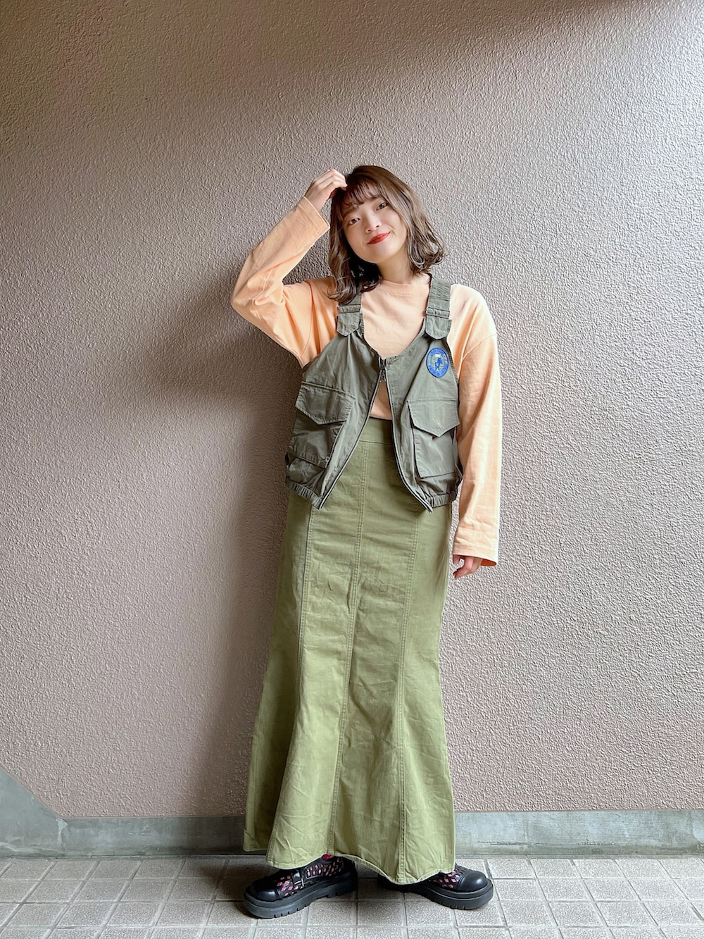 グリーン系のベスト、グリーン系のスカート、ブラック系のその他シューズを着用したレディースの春コーディネートの4枚目の写真