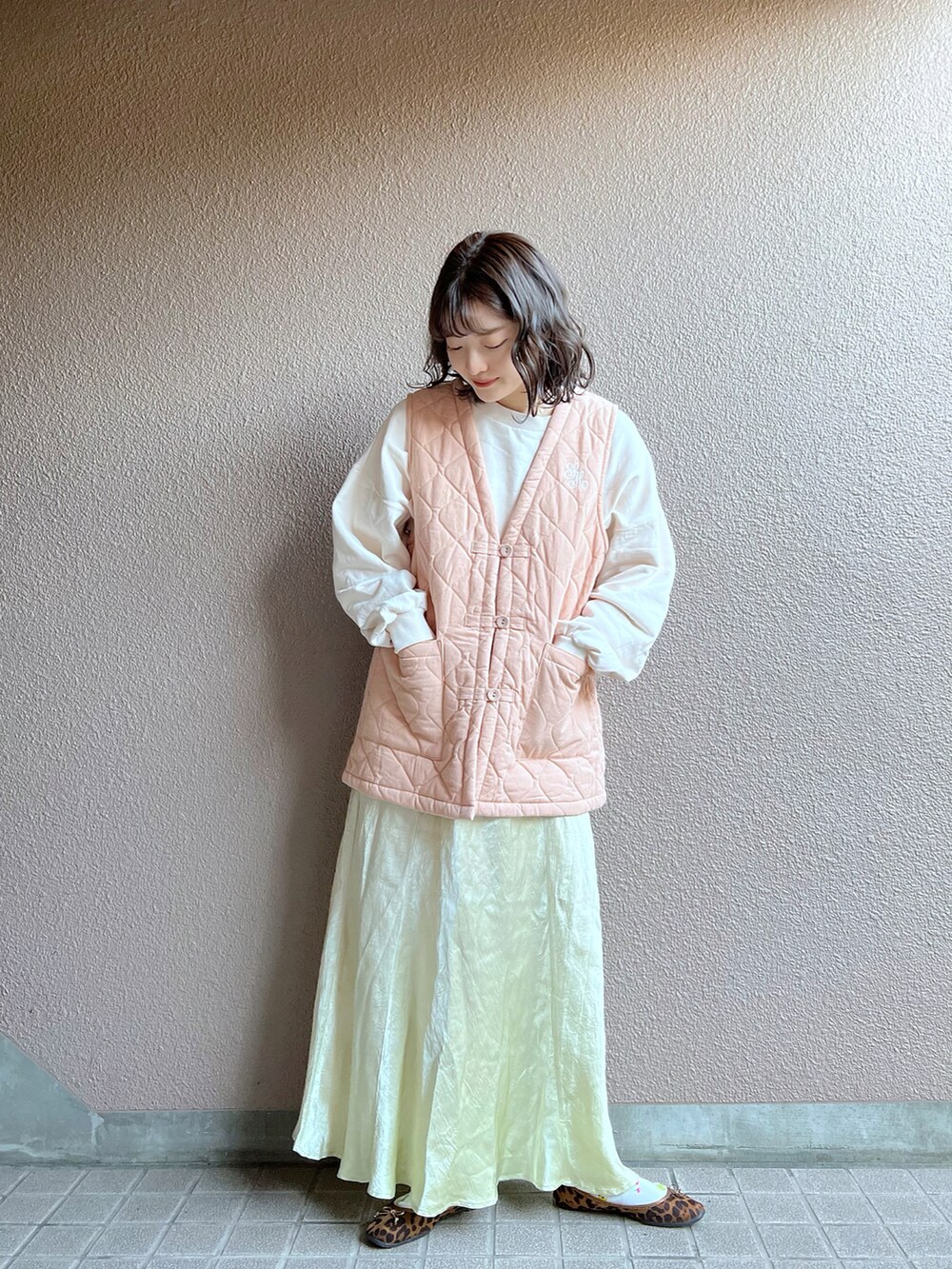 ピンク系のベスト、ベージュ系のスカートを着用したレディースの冬コーディネートの2枚目の写真