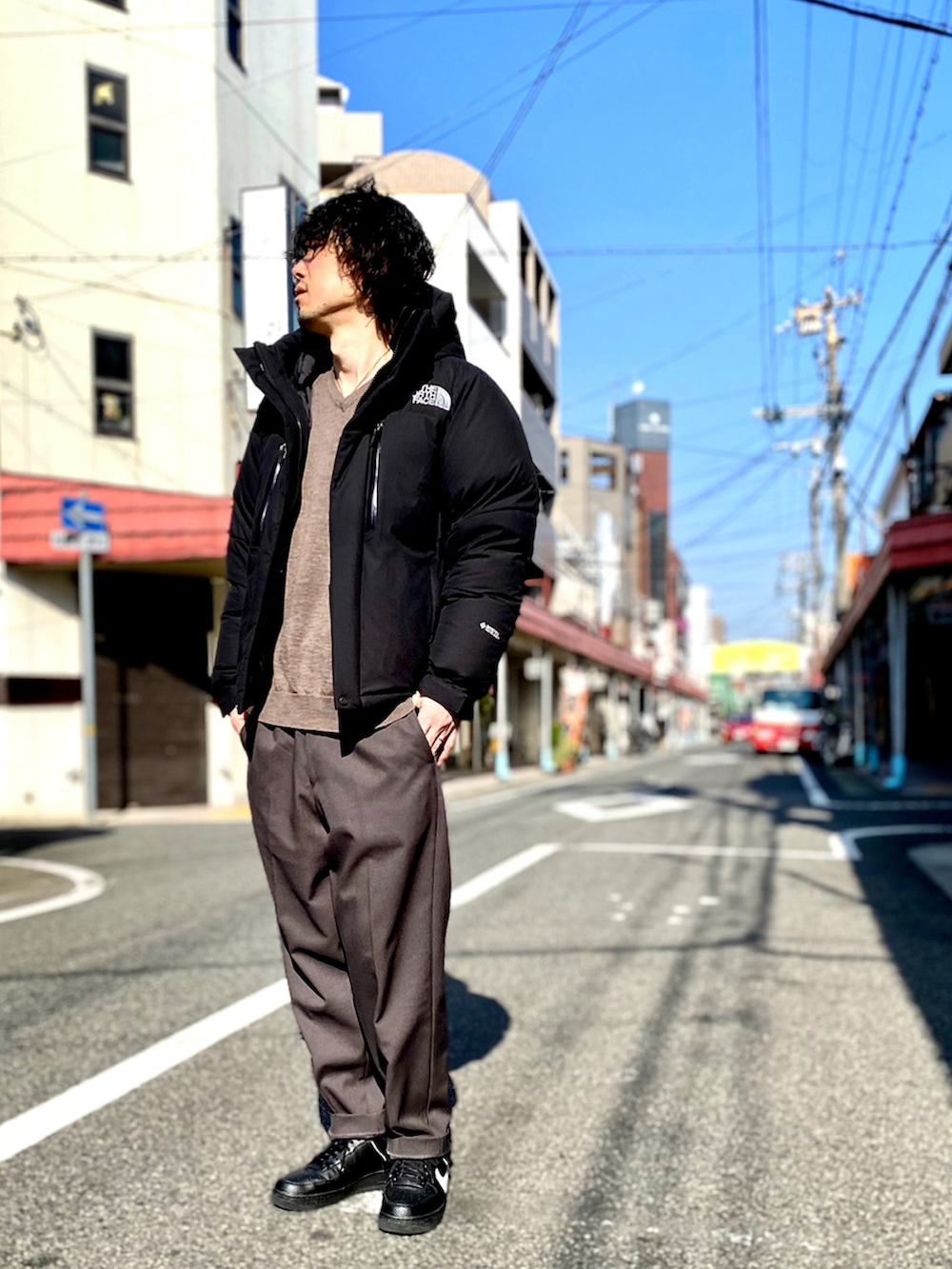 ブラック系のブルゾン、ブラウン系のニット/セーター、ブラウン系のスラックスを着用したメンズの冬コーディネートの2枚目の写真