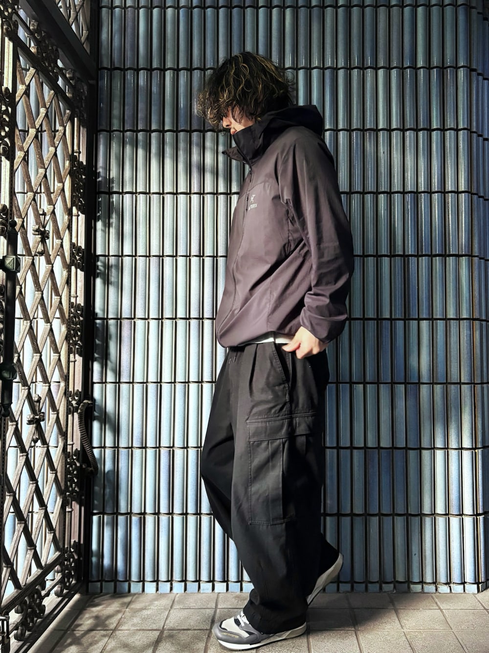 ブラック系のナイロンジャケット、ブラック系のカーゴパンツ、グレー系のスニーカーを着用したメンズの秋コーディネートの4枚目の写真