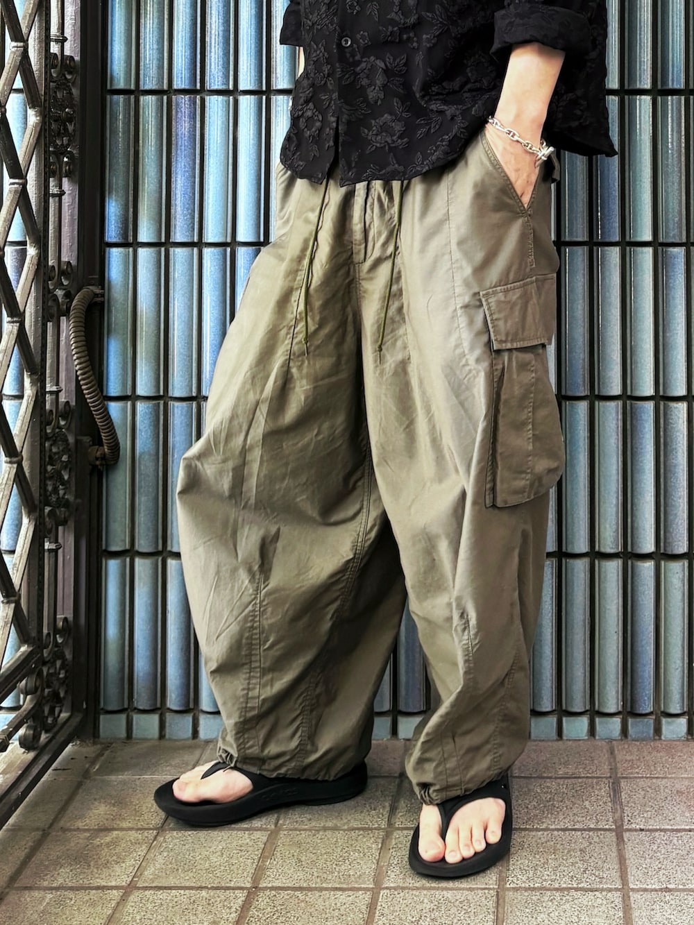 グリーン系のカーゴパンツ、ブラック系のサンダル、ブラック系のシャツ/ブラウスを着用したメンズの夏コーディネートの3枚目の写真