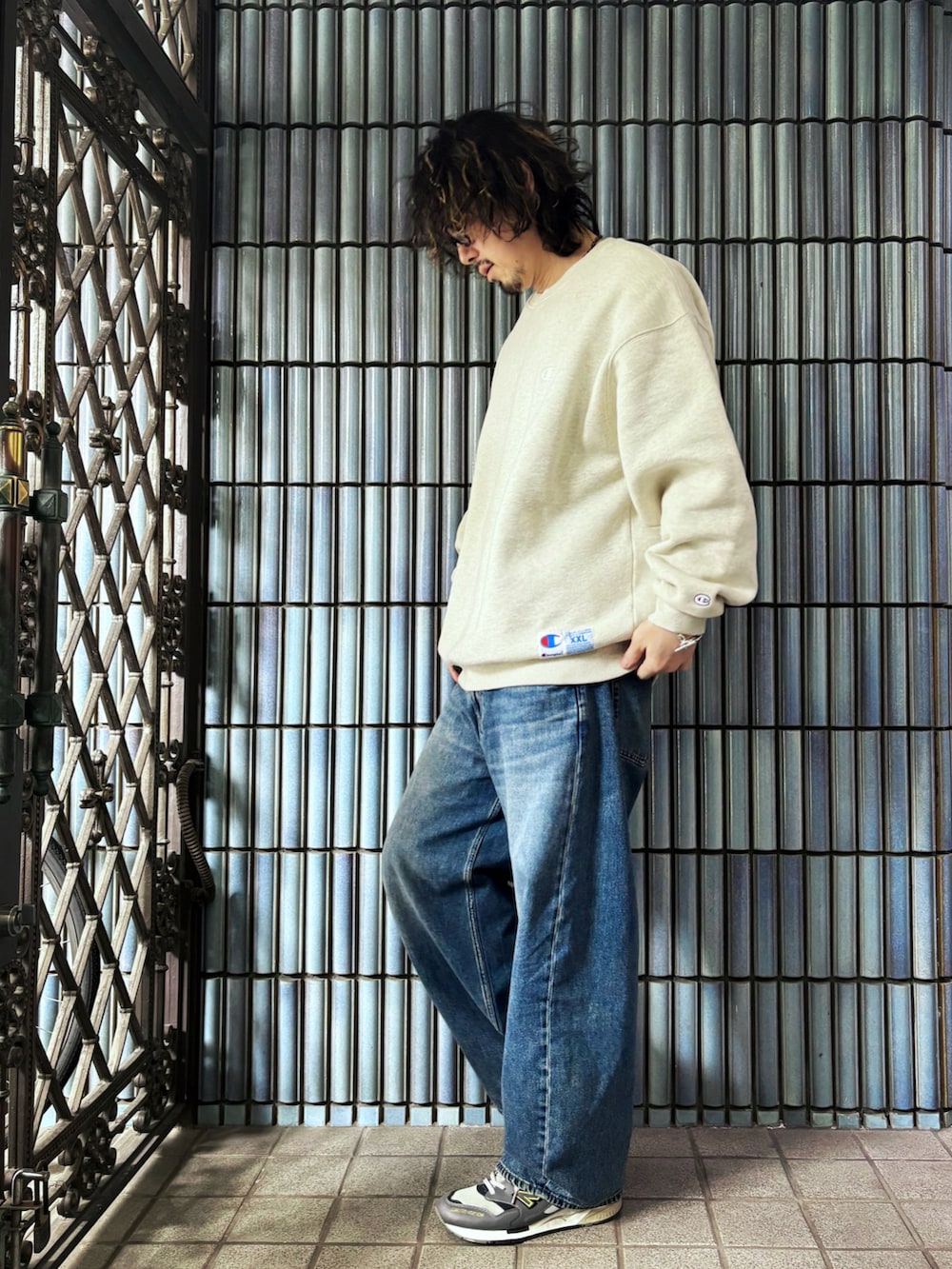 ベージュ系のスウェット、グレー系のスニーカー、ブルー系のデニムパンツを着用したメンズの春コーディネートの4枚目の写真