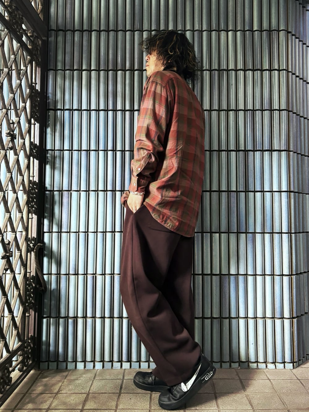 ブラック系のスニーカー、オレンジ系のシャツ/ブラウス、ブラウン系のスウェットパンツを着用したメンズの秋コーディネートの4枚目の写真