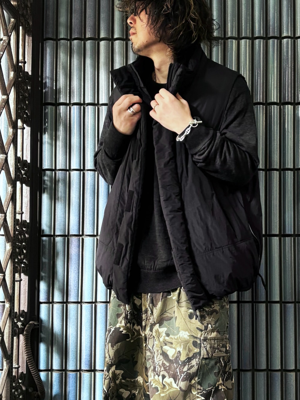 ブラック系のダウンベスト、グリーン系のカーゴパンツ、ブラック系のスニーカーを着用したメンズの冬コーディネートの2枚目の写真