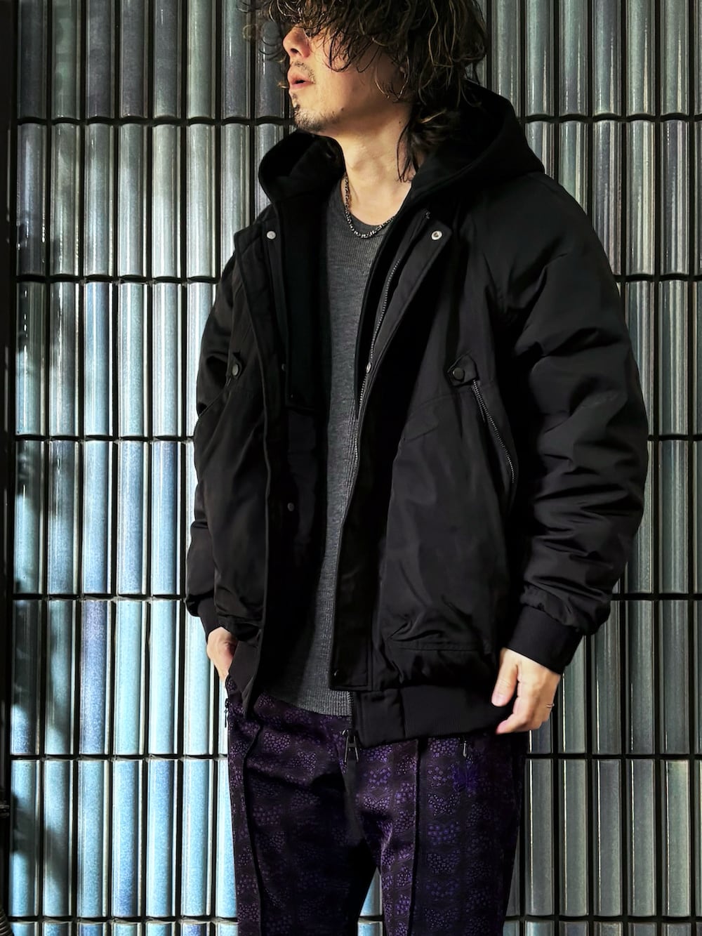 ブラック系のスニーカー、ブラック系のミリタリージャケット、パープル系のその他パンツを着用したメンズの冬コーディネートの2枚目の写真