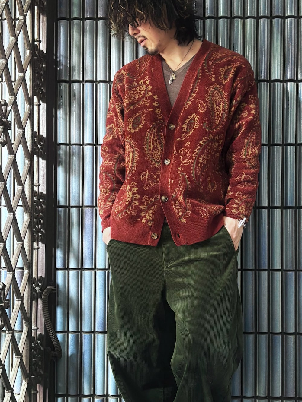 レッド系のカーディガン/ボレロ、ブラウン系のニット/セーター、ブラック系のスニーカーを着用したメンズの春コーディネートの2枚目の写真