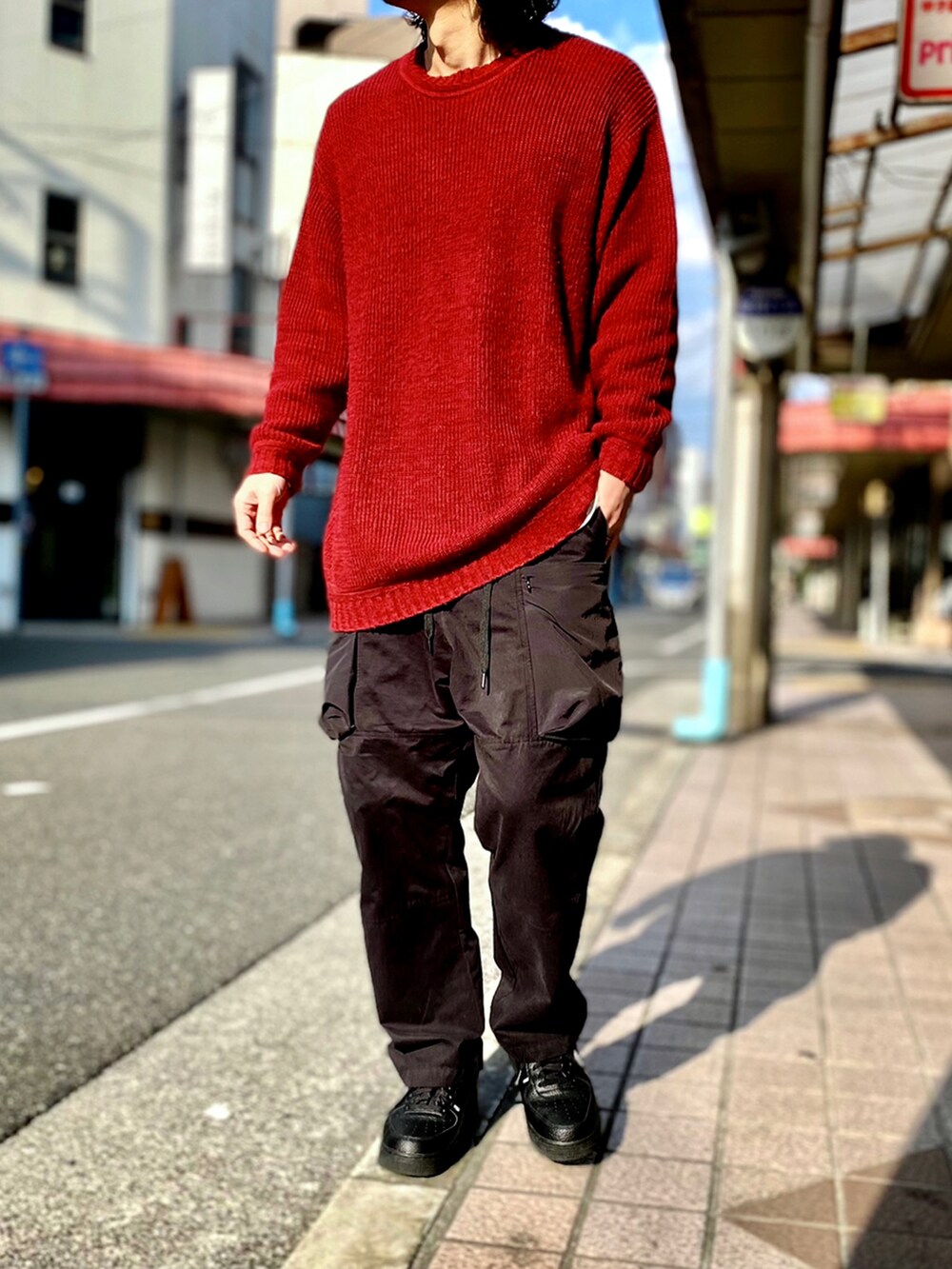 レッド系のニット/セーター、ブラック系のカーゴパンツ、ブラック系のスニーカーを着用したメンズの冬コーディネートの2枚目の写真