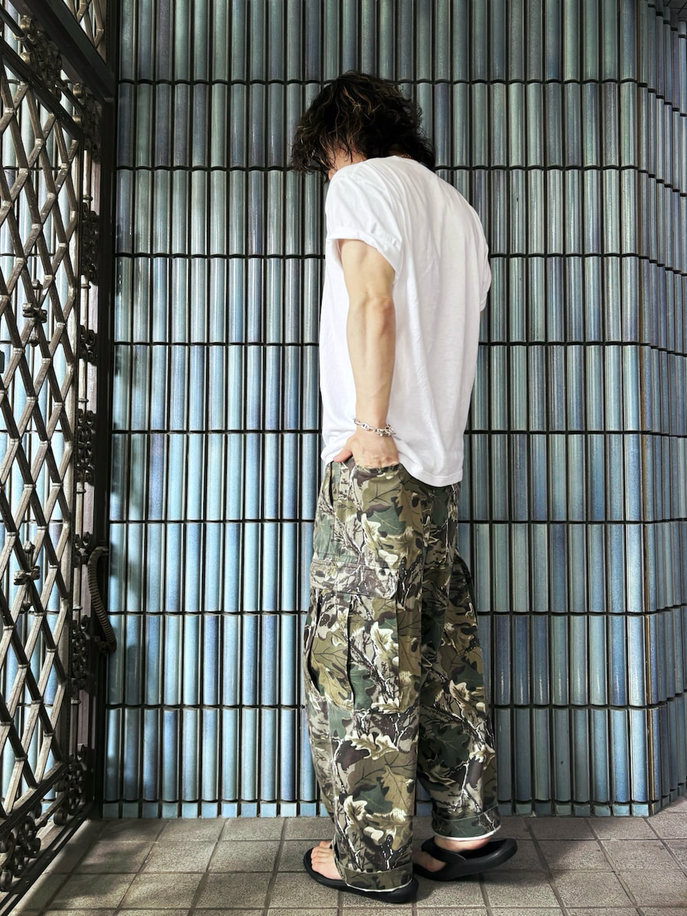 ブラック系のサンダル、グリーン系のカーゴパンツ、ホワイト系のTシャツ/カットソーを着用したメンズの夏コーディネートの4枚目の写真
