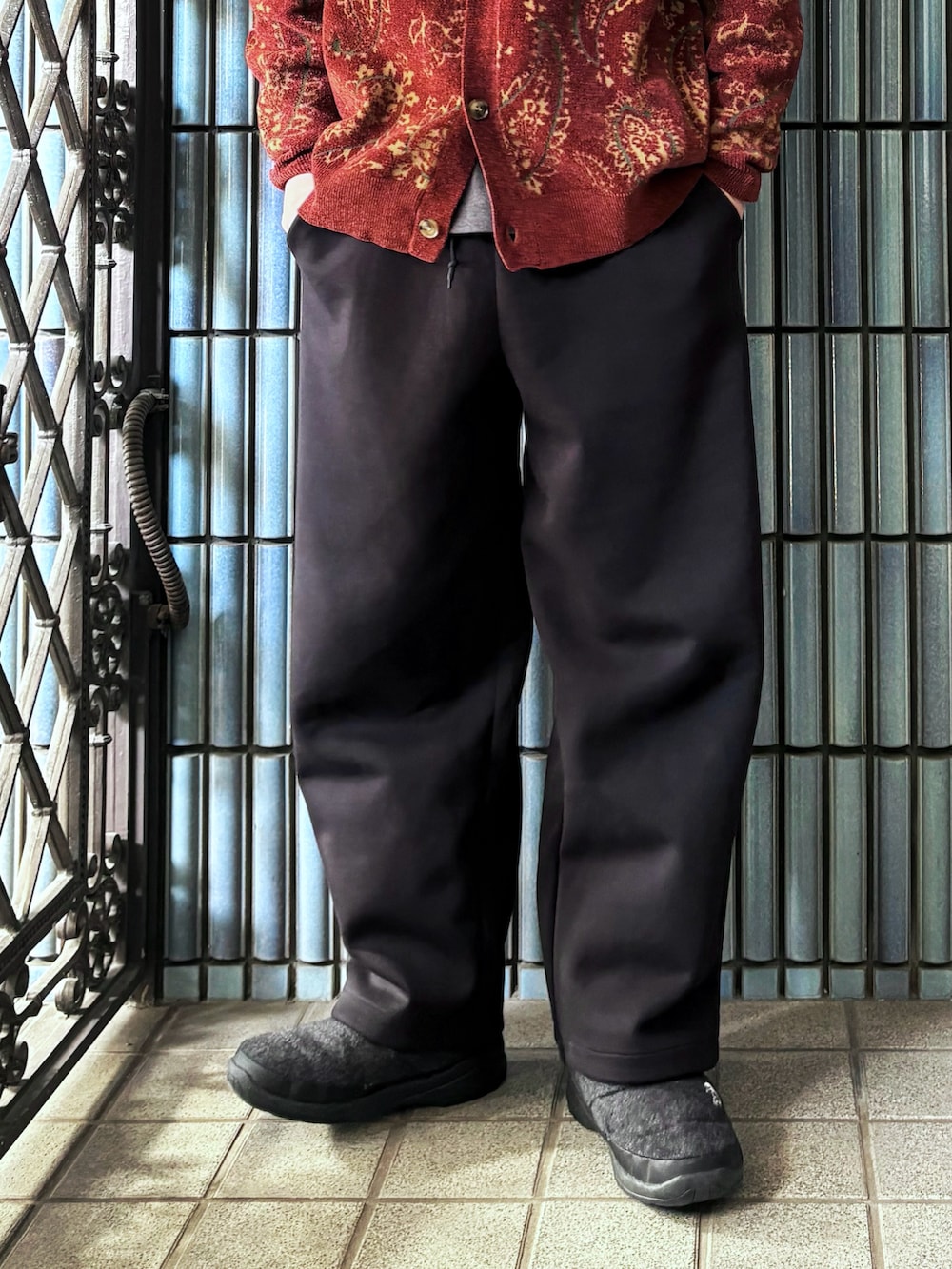 レッド系のカーディガン/ボレロ、ブラック系のスウェットパンツ、グレー系のブーツを着用したメンズの冬コーディネートの3枚目の写真