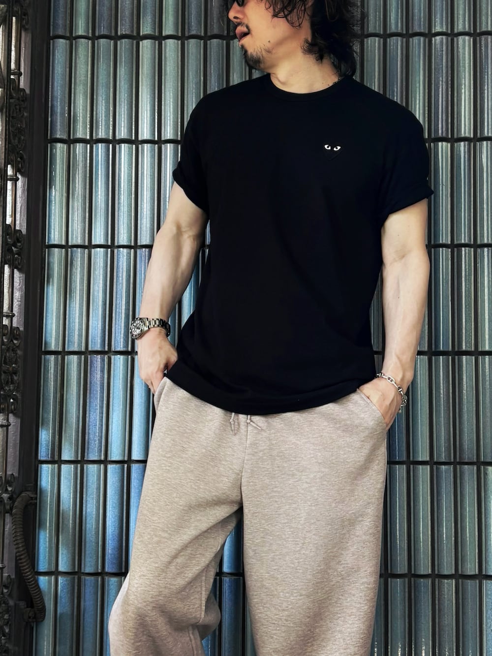 ブラック系のサンダル、ブラック系のTシャツ/カットソー、ベージュ系のスウェットパンツを着用したメンズの夏コーディネートの2枚目の写真