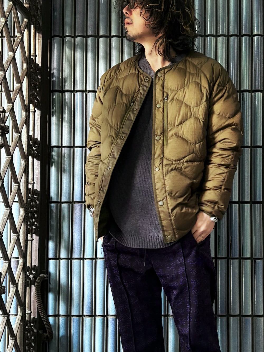 ブラック系のスニーカー、グレー系のニット/セーター、グリーン系のダウンジャケット/コートを着用したメンズの冬コーディネートの2枚目の写真