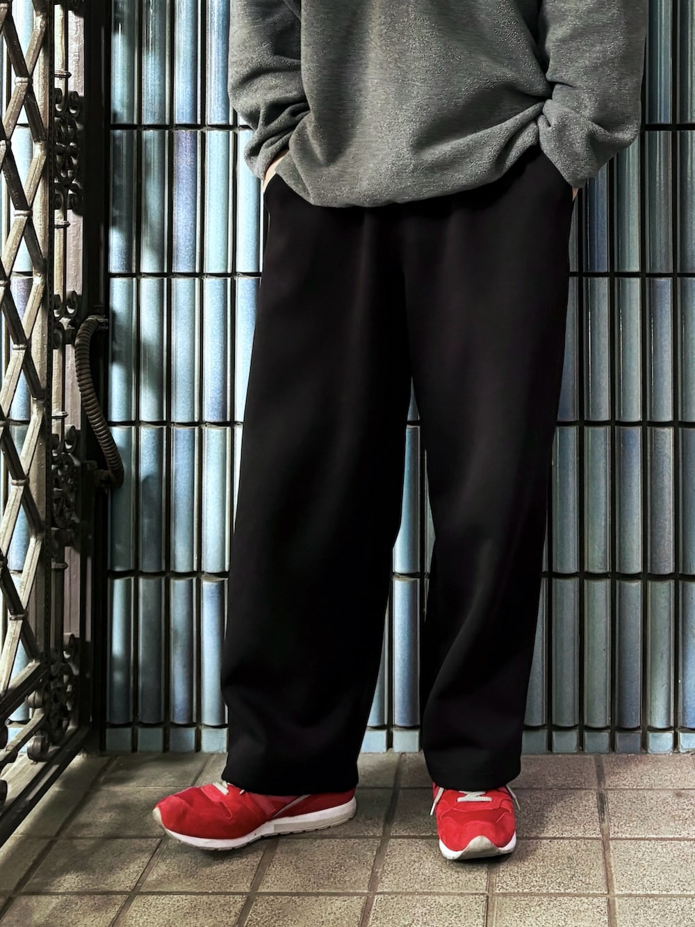 グレー系のニット/セーター、レッド系のスニーカー、ブラック系のスウェットパンツを着用したメンズの春コーディネートの3枚目の写真