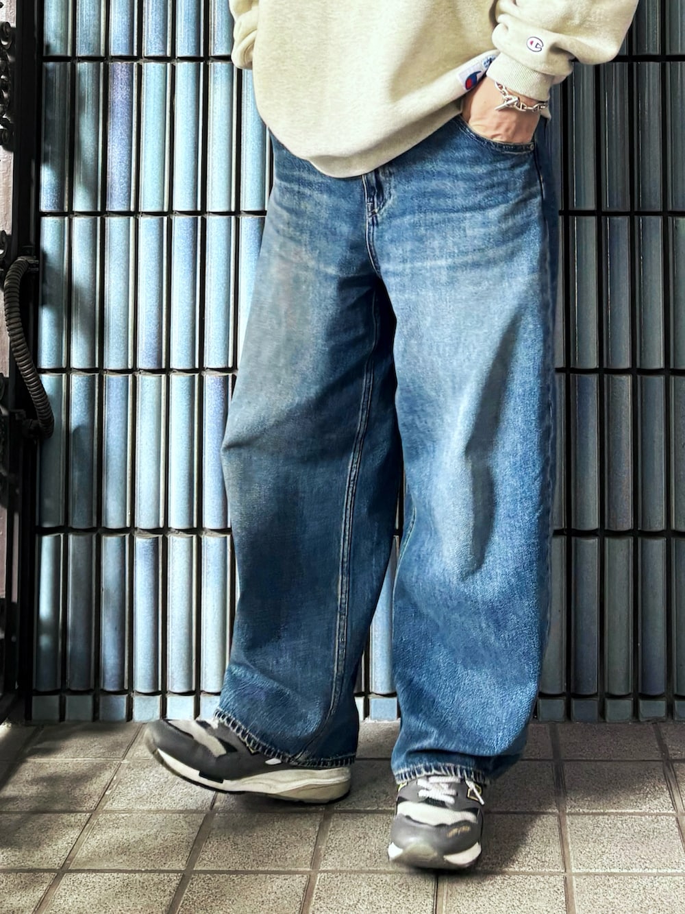 ベージュ系のスウェット、グレー系のスニーカー、ブルー系のデニムパンツを着用したメンズの春コーディネートの3枚目の写真