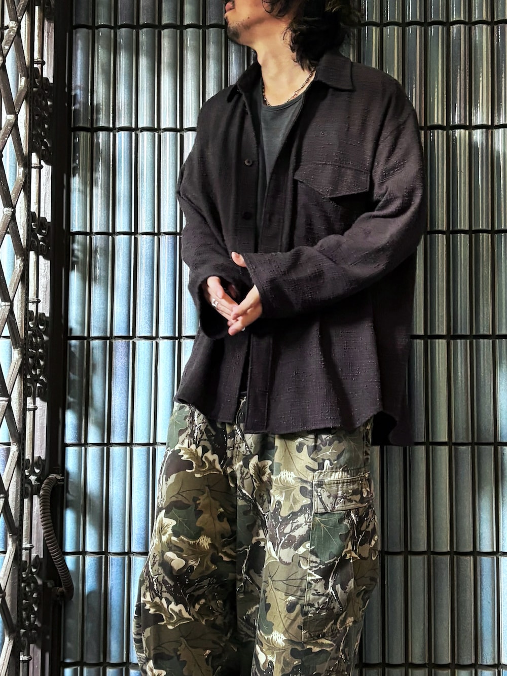 グリーン系のカーゴパンツ、グレー系のスニーカー、ブラック系のシャツ/ブラウスを着用したメンズの秋コーディネートの2枚目の写真